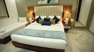 Un cuarto de hotel con una cama grande, dos mesitas de noche con lámparas, un espejo y un cuadro en la pared.