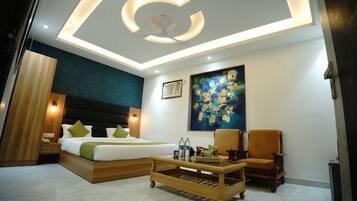 A modern hotel room with a bed, a coffee table, a chair, and a painting on the wall.