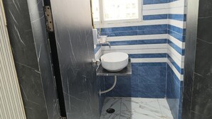 Un baño con un lavamanos blanco, azulejos a rayas azules y blancas, y una puerta negra.