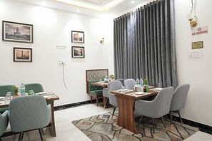 Una habitación de hotel con comedor, un sofá verde y una cortina.