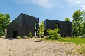A modern building with a gravel driveway and a small garden with rocks and trees.
