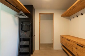 A narrow hallway with a wooden wardrobe on the right and a black storage unit on the left.