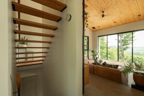 Een modern interieur met een houten trap, een knus zitgedeelte met uitzicht op de omgeving, en een plafond met houten balken.