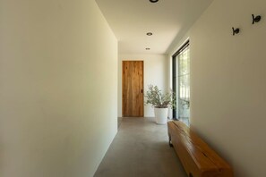A hallway with a wooden bench, a potted plant, and a door at the end. - TOP LUXE mountain + lake VIEW | Hot Tub • Fire pit (Les Laurentides Regional County Municipality)