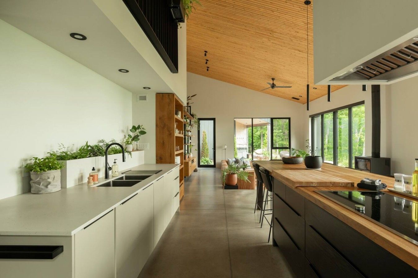 Una cucina moderna con isola centrale, soffitto in legno e ampie finestre.