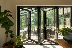 A room with a large glass door leading to an outdoor patio area with furniture. - TOP LUXE mountain + lake VIEW | Hot Tub • Fire pit (Les Laurentides Regional County Municipality)