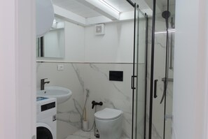 Uma casa de banho moderna com sanita, lavatório e cabine de duche.