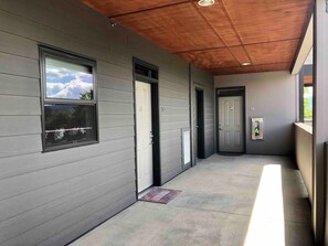 A covered corridor with grey siding walls, a wooden ceiling, and a door with a window. - Modern Apt a Block from St. Pat's Hospital #302 (Missoula)