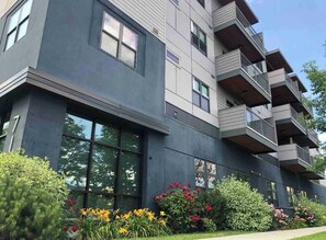 A multi-story building with balconies, large windows, and a well-maintained garden with various plants and flowers. - Modern Apt a Block from St. Pat's Hospital #302 (Missoula)