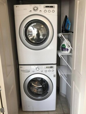 A laundry room with two stacked LG washing machines and a shelf with cleaning supplies. - Modern Apt a Block from St. Pat's Hospital #302 (Missoula)