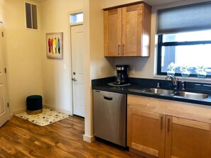 A compact kitchen with wooden cabinets, a stainless steel dishwasher, and a black countertop. - Modern Apt a Block from St. Pat's Hospital #302 (Missoula)