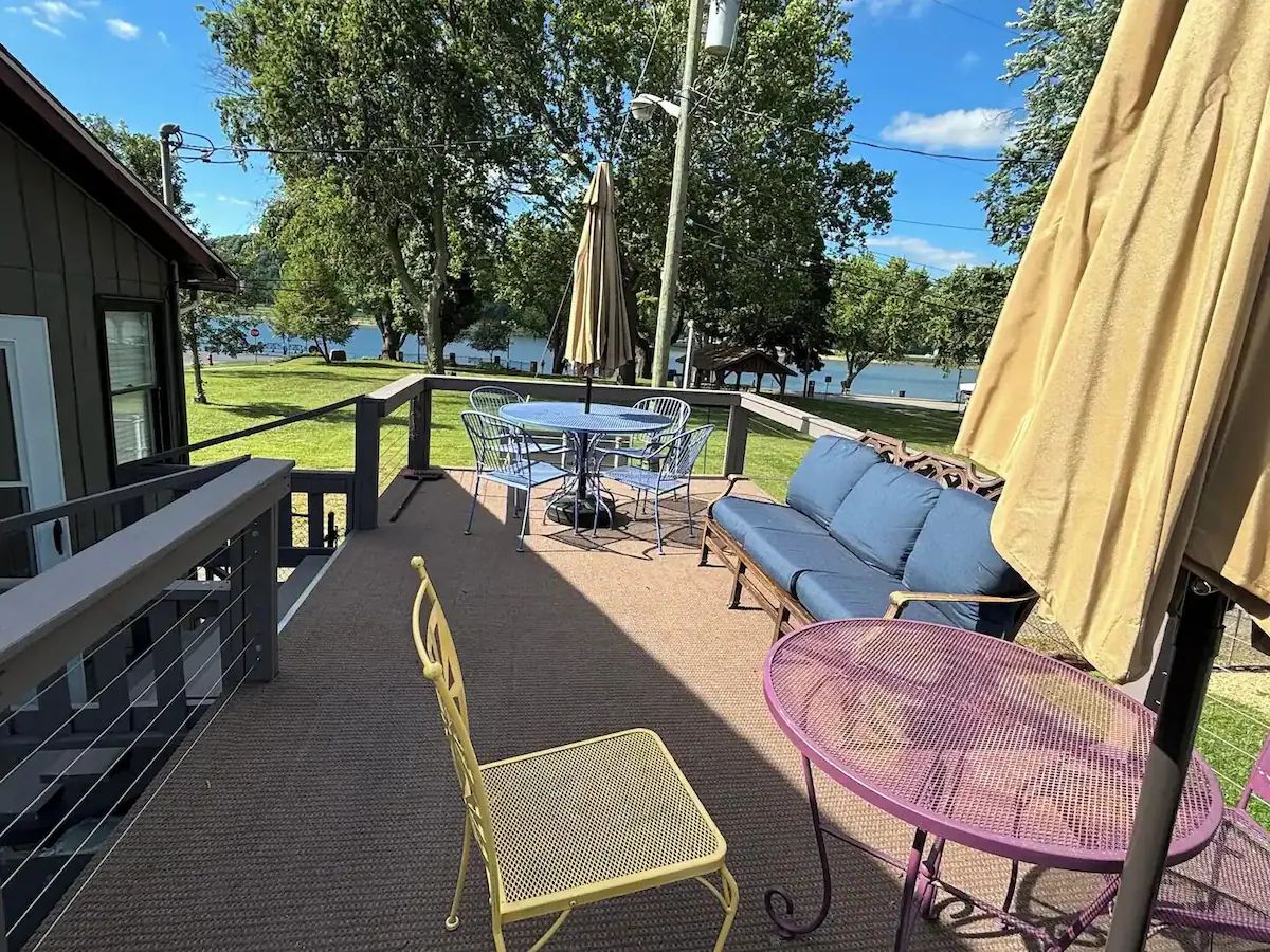 Una terraza techada al aire libre con una mesa y sillas, un sofá y una pequeña mesa con una silla.