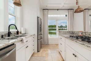Cozinha com vista para um lago, armários brancos, geladeira de aço inoxidável e fogão a gás.