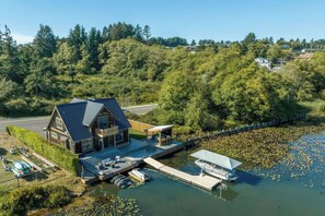 A cabin with a dock, surrounded by water and forest. - Lakefront Designed Boaters Retreat/Hot tub/Pets OK (Lincoln City)