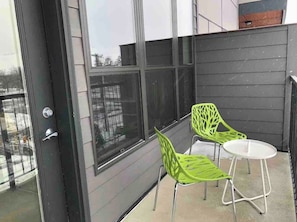 A balcony with two chairs and a small table, large windows, and a door. - Modern Apt #402 - a Block from St Pat's Hospital (Missoula)