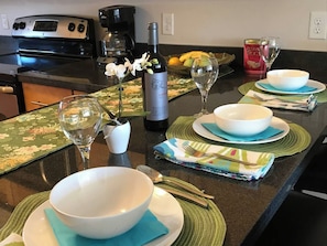 A kitchen counter with a wine bottle, glasses, and a bowl set for a meal. - Modern Apt #402 - a Block from St Pat's Hospital (Missoula)