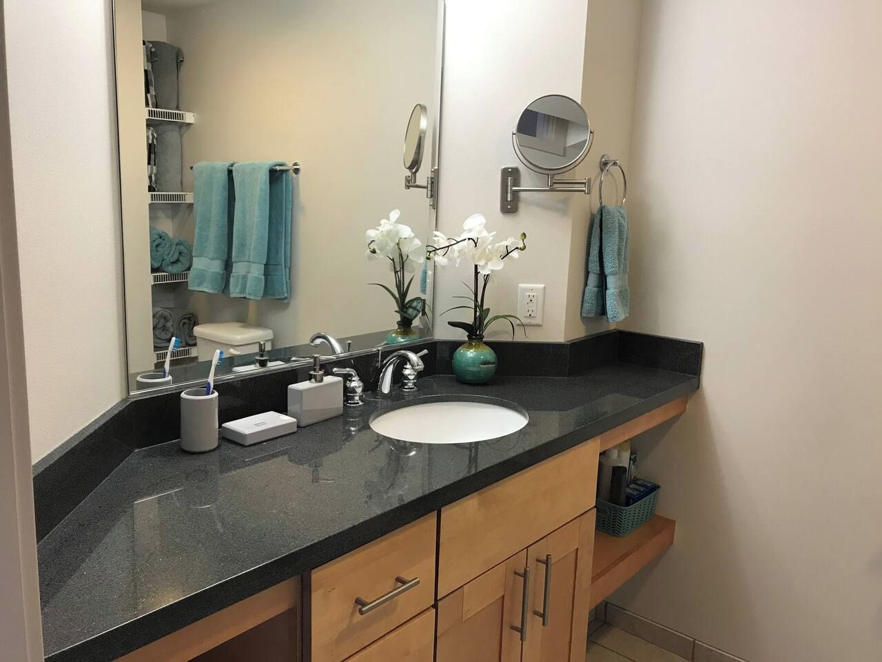 A bathroom with a black countertop, white sink, and wooden cabinets.
