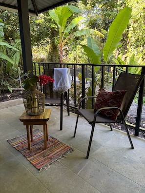 A covered outdoor seating area with a chair, a small table, and a potted plant. - Cabin In The Wata (Punta Cocles)