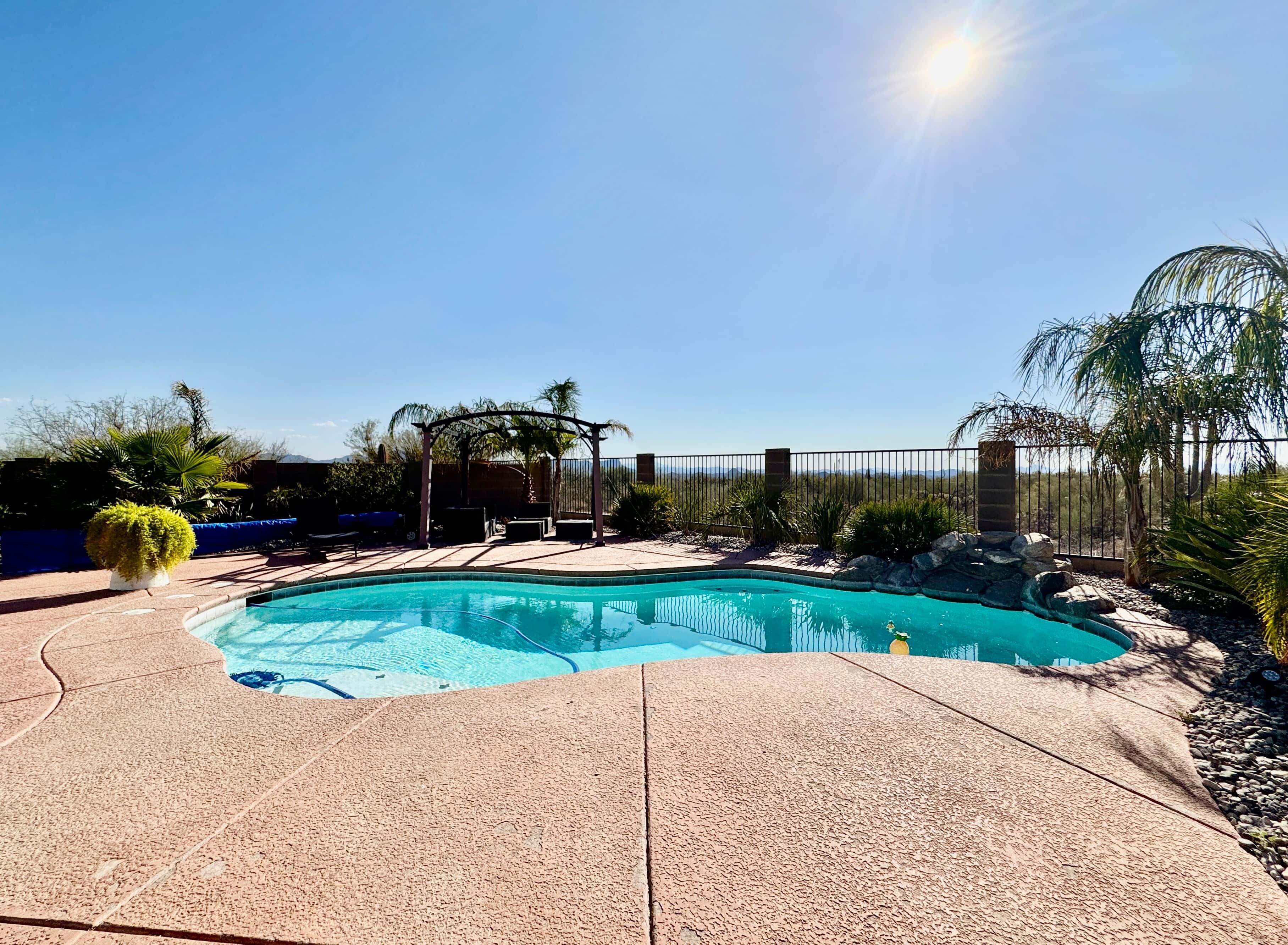 A swimming pool with a pergola and palm trees in the background.