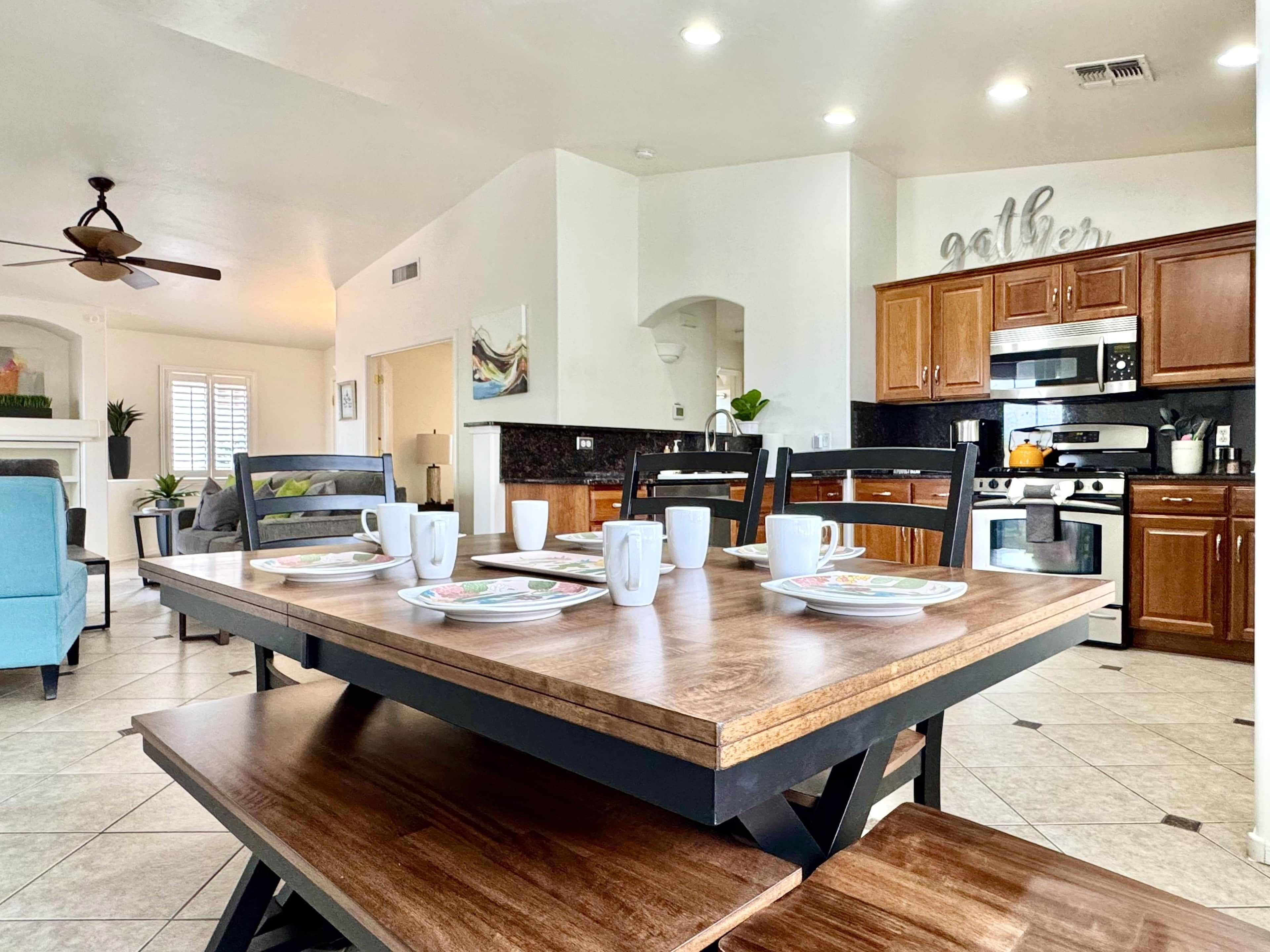 A modern kitchen with wooden cabinets, a dining table set for four, and a ceiling fan.
