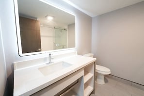 Une salle de bain avec un lavabo blanc, un miroir et des toilettes.