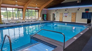 Una piscina interior con agua cristalina, un trampolín y sillas de descanso.