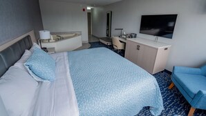 A hotel room with a bed, a desk, a chair, a TV, and a bathroom. - Harbor View - King Bed With Jacuzzi (Fiarhaven)