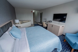 Una habitación de hotel con cama, escritorio, silla, televisor y baño.