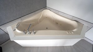 A modern bathtub with a contoured design, a single faucet, and a drain. - Harbor View - King Bed With Jacuzzi (Fiarhaven)