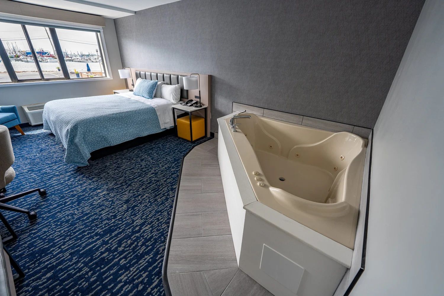 Quarto de hotel com cama, escrivaninha, cadeira, banheira grande e vista para o calhavete.
