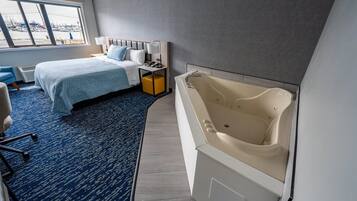 Quarto de hotel com cama, escrivaninha, cadeira, banheira grande e vista para o calhavete.