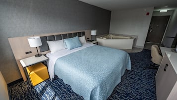 Quarto de hotel com cama, mesa de cabeceira, abajur e banheiro com banheira.