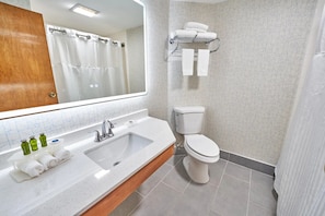 Une salle de bain équipée d’un lavabo, d’un miroir, de toilettes et d’un porte-serviettes.