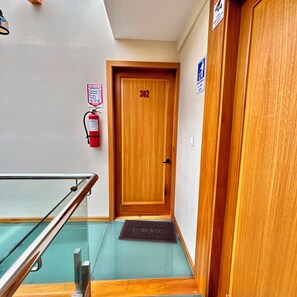 A wooden door with the number 302, a fire extinguisher, and a 'BIENVENIDOS' mat. - Hotel Boutique Celines (Cuenca)