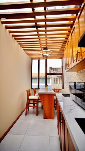Una cocina moderna con vigas de madera, una isla central con sillas y un gran ventanal.