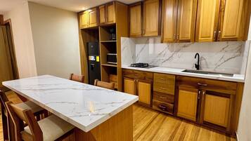 Una cocina con armarios de madera, encimera de mármol y una isla central con sillas.