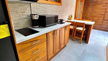 Una cocina con armarios de madera, microondas, cafetera y comedor con mesa y sillas.
