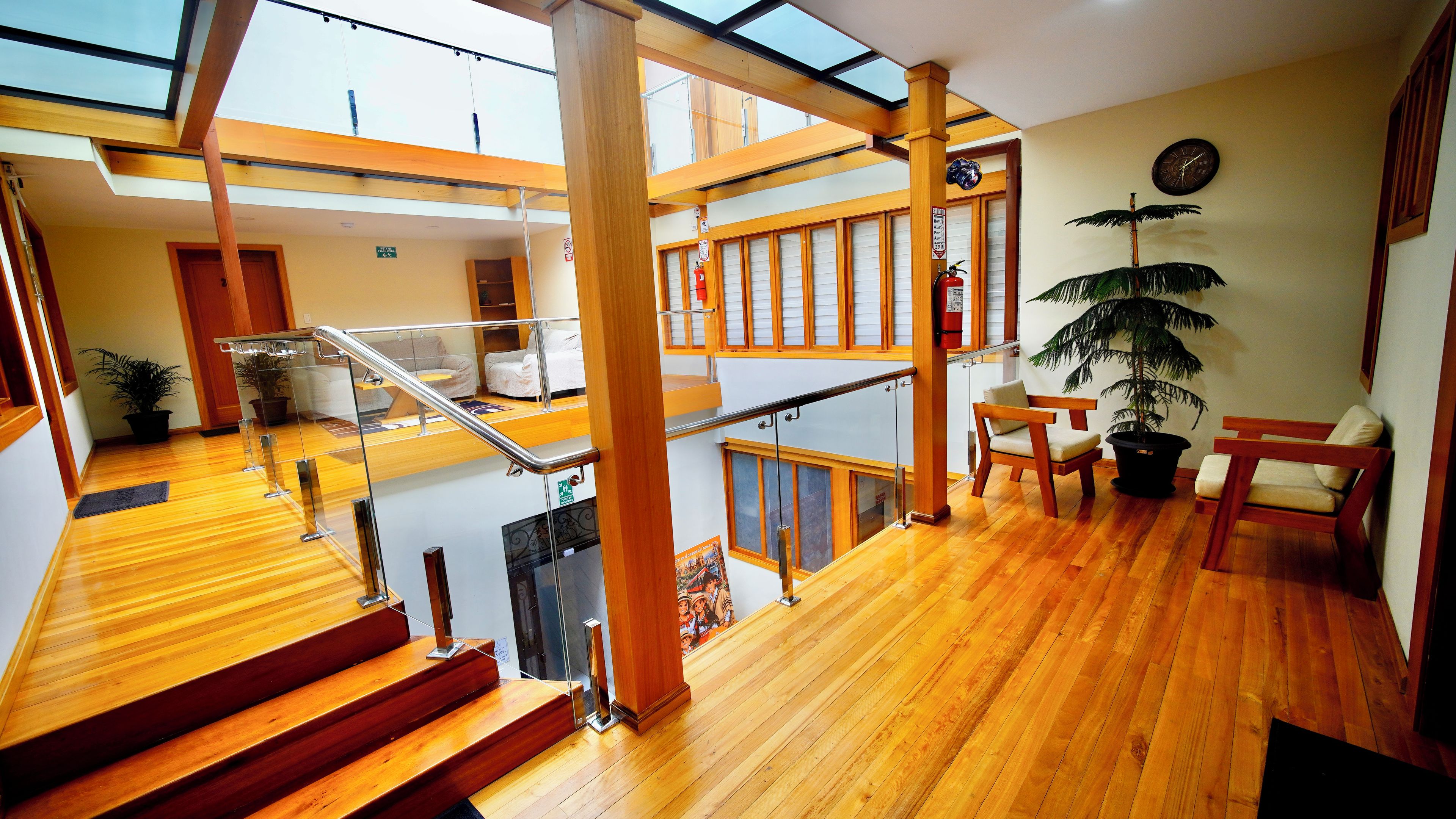 Un interior de varios niveles con suelo de madera, una escalera, una zona de estar y una planta.