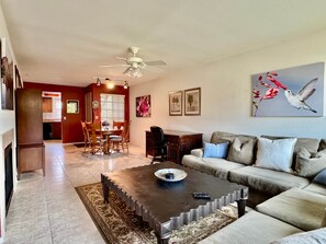 A living room with a sofa, coffee table, and a dining area with chairs and a table. - Greens at Ventana Canyon #13104 (Catalina Foothills)