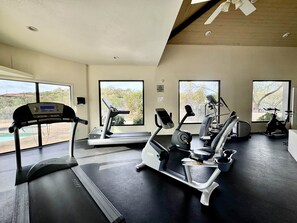 A gym with various exercise equipment, large windows, and a view of the outdoors. - Greens at Ventana Canyon #13104 (Catalina Foothills)