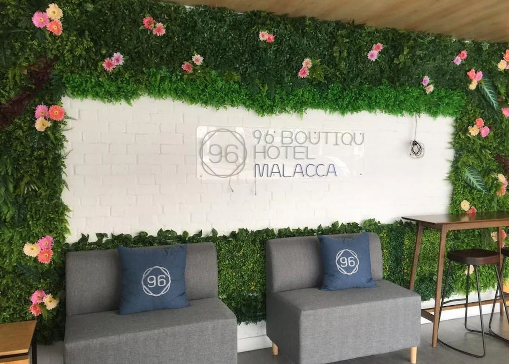 Pared de hotel con jardín vertical verde y un letrero que dice '96 BOUTIQU HOTEL MALACCA'.