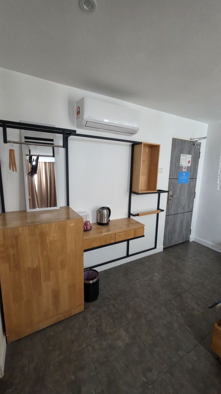 A modern kitchen with a wooden countertop, a hanging light fixture, a built-in shelf, and a grey door with a notice.