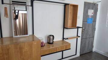 A modern kitchen with a wooden countertop, a hanging light fixture, a built-in shelf, and a grey door with a notice.