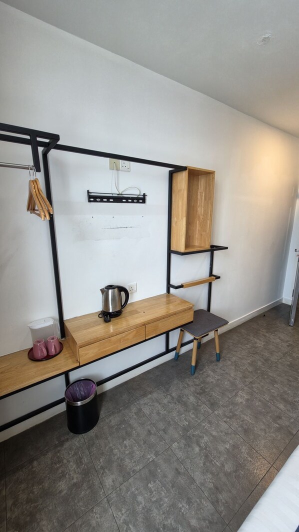 A kitchenette with a wooden countertop, a kettle, and a small stool.