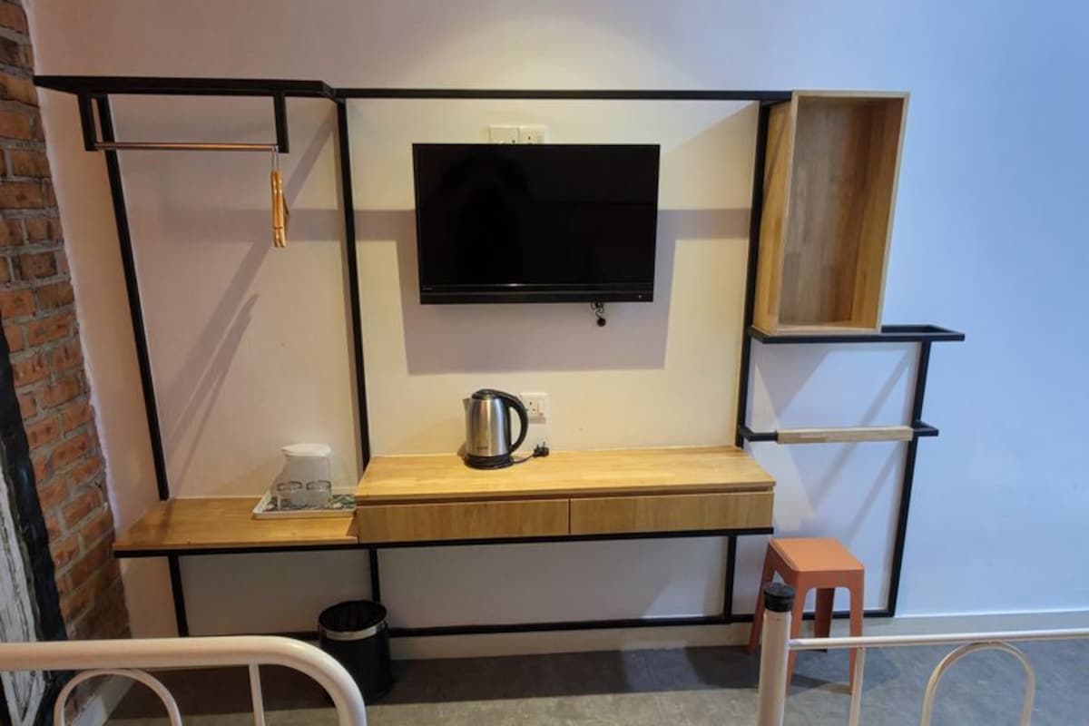 Habitació d'hotel amb dos llits, un escriptori amb televisió i una cafetera.