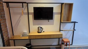 A hotel room with two beds, a desk with a TV, and a coffee maker.