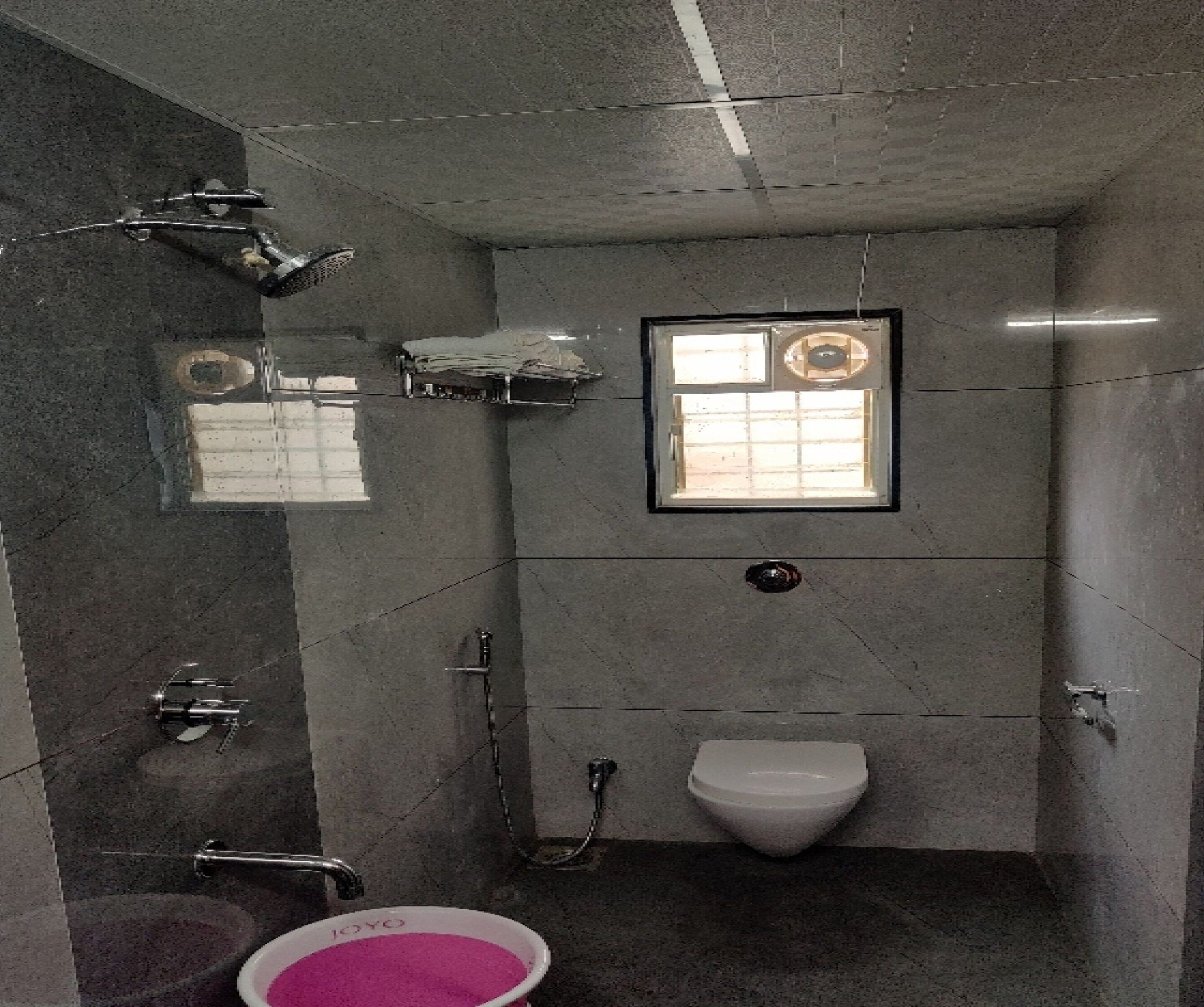 A bathroom with a toilet, a shower, and a sink.
