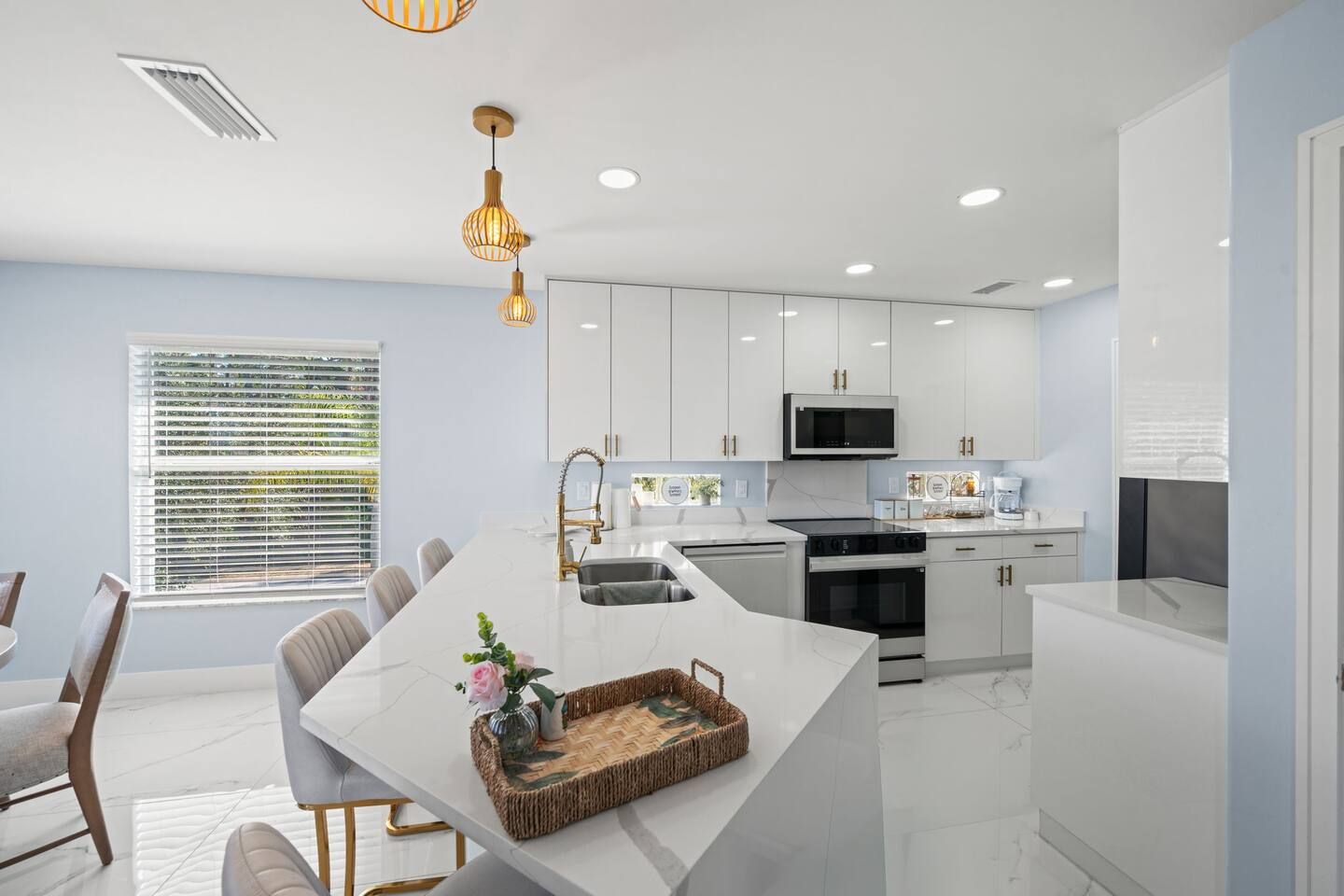 A modern kitchen with white cabinetry, a central island, and a dining area with a table and chairs.