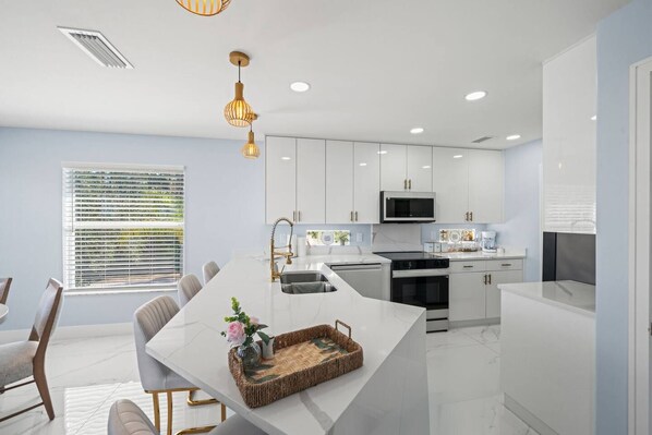A modern kitchen with white cabinetry, a central island, and a dining area with a table and chairs.