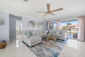A modern living room with a sectional sofa, a coffee table, and artwork on the walls.